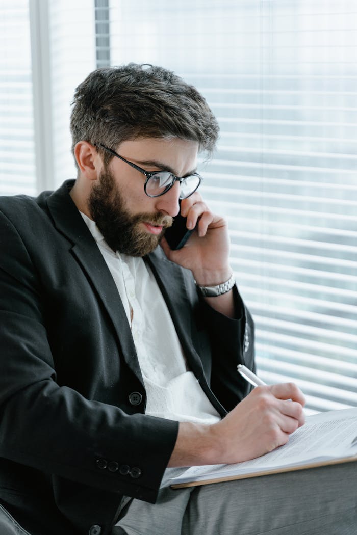 gallery-01 Focused businessman in office, analyzing documents while on a phone call.