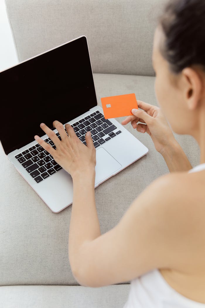 our-story Woman holding credit card making online purchase on laptop computer, representing e-commerce.